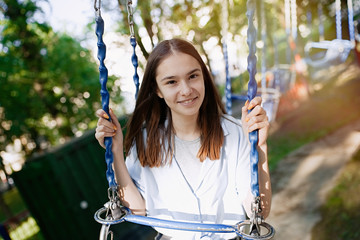 Happy child teenage girl riding chain carousel swing at amusement park    