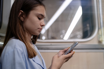 Teen girl rides the subway and used smartphone          