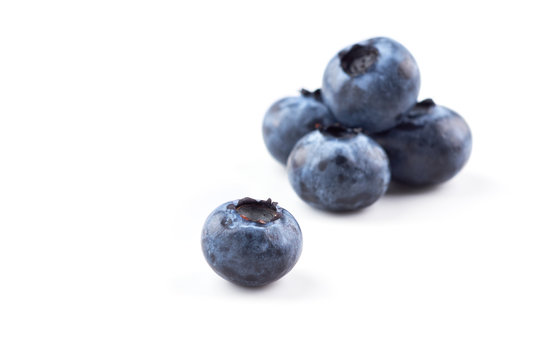 A group of blueberries on a white background, one blueberry berry in the foreground. Close up.