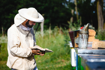 Beekeeper working in his apiary and looking to his bee diary