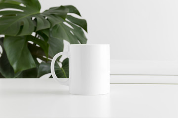 Mug mockup with workspace accessories and a monstera plant.