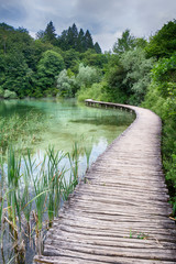 Fototapeta na wymiar Jezero s křišťálově čistou vodou, přes kterou vede dřevěná lávka.