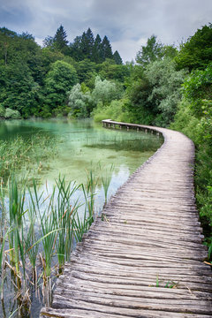 Jezero s kři&scaron;ť&aacute;lově čistou vodou, přes kterou vede dřevěn&aacute; l&aacute;vka.