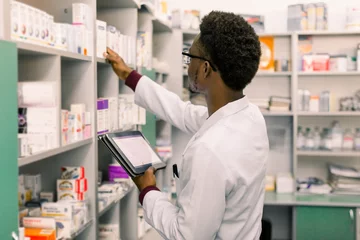Printed roller blinds Pharmacy African American male pharmacist using digital tablet during inventory in pharmacy.