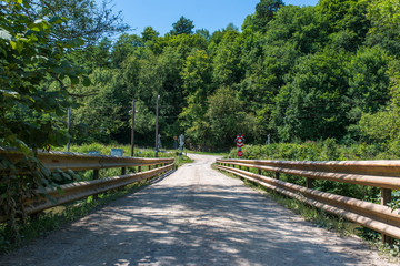Old bridge, dirt road over Olt river in Transylvania, Romania, railways crossing with lights in the background.