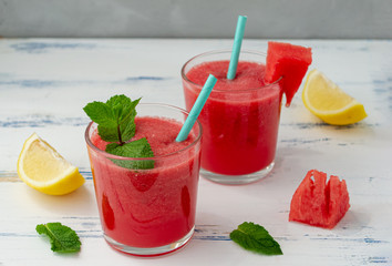 Cold watermelon smoothie with mint and lemon in glasses. A cocktail of watermelon juice on a light blue background.