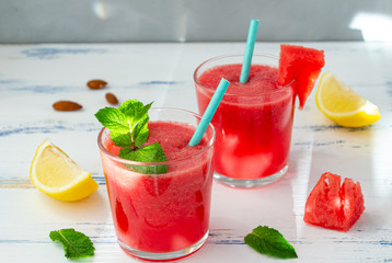Cold watermelon smoothie with mint and lemon in glasses. A cocktail of watermelon juice on a light blue background.