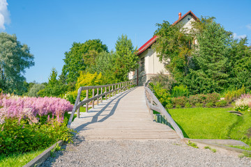 Wooden footbridge to the house among the flowers.
