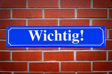 Wichtig Schild blau an Backsteinwand