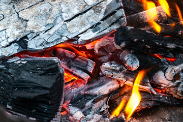 Closeup of burning and smoldering firewood. Close-up of Burning coal. Glowing embers smoldering in the fireplace. Burning log of wood close-up as abstract background.