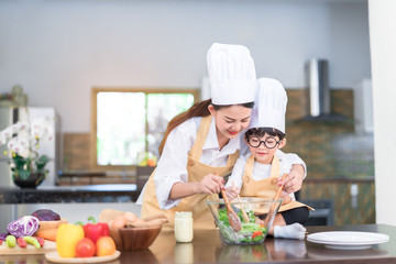 Professional Chef asian mom teaching little son cooking salad vegetable prepare healthy food in the kitchen room for dinner at home happy family lifestyle.