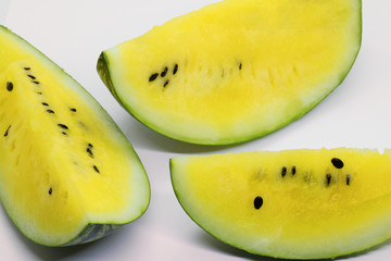 close-up of some pieces of refreshing watermelon on white background, yellow watermelon with mint leaves and ice pieces