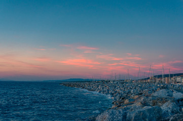 Fototapeta na wymiar Romantic coastal sunset seascape with blue sky and bright pink clouds