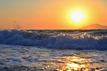 Beautiful sunset with sea and waves. Natural colorful background. Concept for summer and sea vacation. Greece - island of Kos.