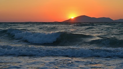 Beautiful sunset with sea and waves. Natural colorful background. Concept for summer and sea vacation. Greece - island of Kos.