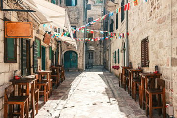 Old historical buildings with street cafe in the central district of ancient city Kotor in...