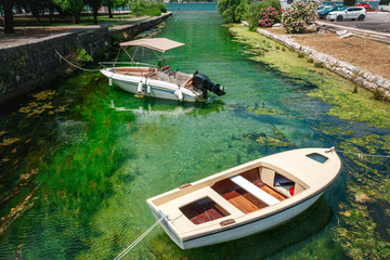 Two small boats in the saturated green water in the Kotor town, Montenegro