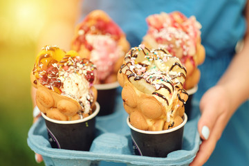 four Hong Kong waffles in cups food delivery in hand of woman
