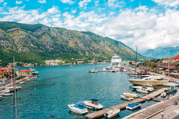 Fototapeta na wymiar Ancient town Kotor with marina and yachts on the water, old stone houses surrounded by mountains, Montenegro
