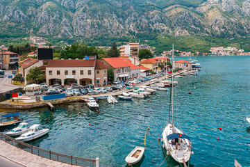 Ancient town Kotor with marina and yachts on the water, old stone houses surrounded by mountains,...