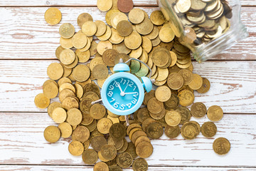 Savings for the future. Malaysia coins and clock on wooden background. Shallow depth of field