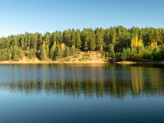 Obraz premium autumn forest with reflections in calm water