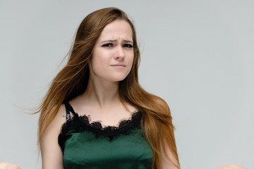 Concept close-up portrait of a pretty girl, young woman with long beautiful brown hair in a green t-shirt on a white background. In the studio in different poses showing emotions.