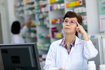 an elderly woman pharmacist she is very sick and forgetful while working at pharmacy
