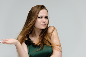 Fototapeta premium Concept close-up portrait of a pretty girl, young woman with long beautiful brown hair in a green t-shirt on a white background. In the studio in different poses showing emotions.
