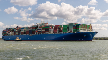 grosses Containerschiff beim einlaufen in den Hafen, in begleitung von schleppschiffen