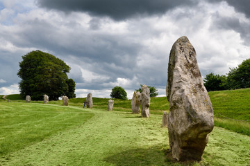Visitor touching a Neolithic standing monolith at Avebury Henge England south west sector edge of the largest megalithic stone circle in the world