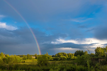 Multicolor rainbow against the dark cloudy sky, Russia.