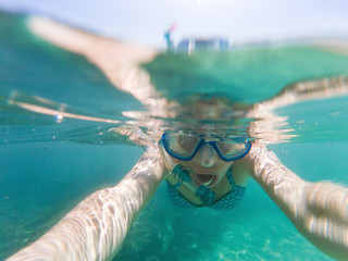 woman taking a selfie snorkeling in clear tropical waters - active holiday