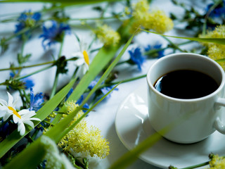 Cup of coffee and wild flowers on light background, top view. Cozy Breakfast. Flat lay .