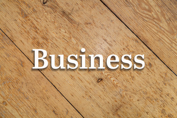`Business` white text on a wooden home background. 