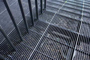 Outside metal stairs framework with handrail. Steps from iron straps and gaps. Industrial structural lines background. Perspective inclined view