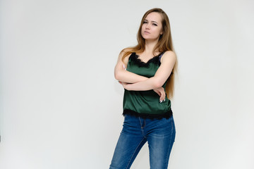 Concept portrait above the knee of a pretty girl, a young woman with long beautiful brown hair and a green t-shirt and blue jeans on a white background. In studio in different poses showing emotions.