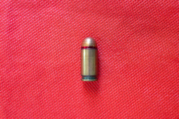 Gun cartridge on red background. Bullet moves vertically. Closeup concept image with copy space