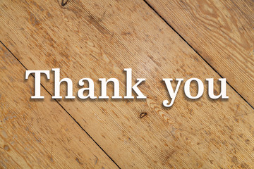 `Thanks you` white text on a wooden home background. 