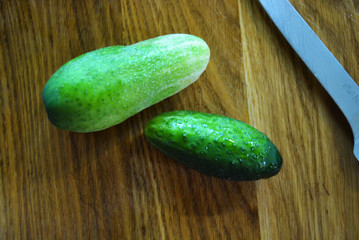 A lot of fresh green tryed cucumbers for salad lay on a wooden kitchen board.