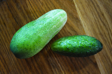 A lot of fresh green tryed cucumbers for salad lay on a wooden kitchen board.
