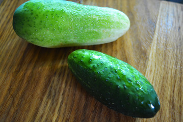 A lot of fresh green tryed cucumbers for salad lay on a wooden kitchen board.