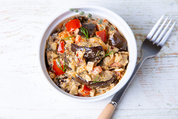 Eggplants with tomatoes, bulgarian red (sweet) pepper, onion, dill and sour cream. Vegetarian dish. Close-up.