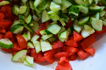 Fresh healthy vegetables, finely chopped green cucumbers and red pomade for summer salad, ingredients for salad.