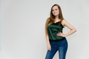 Concept portrait above the knee of a pretty girl, a young woman with long beautiful brown hair and a green t-shirt and blue jeans on a white background. In studio in different poses showing emotions.