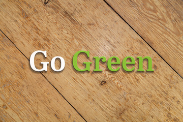 `Go Green` white and green text on a wooden background. 