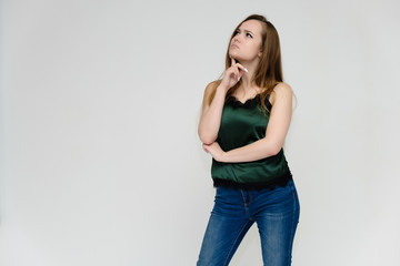 Concept portrait above the knee of a pretty girl, a young woman with long beautiful brown hair and a green t-shirt and blue jeans on a white background. In studio in different poses showing emotions.