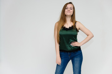Concept portrait above the knee of a pretty girl, a young woman with long beautiful brown hair and a green t-shirt and blue jeans on a white background. In studio in different poses showing emotions.