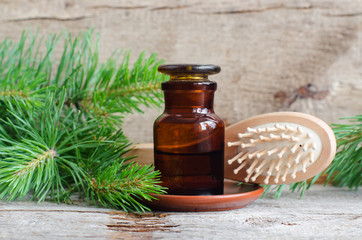 Apothecary bottle with essential pine oil (extract, tincture, infusion) and wooden hair brush. Old wooden background. Aromatherapy, spa, natural hair care and herbal medicine concept. Copy space.