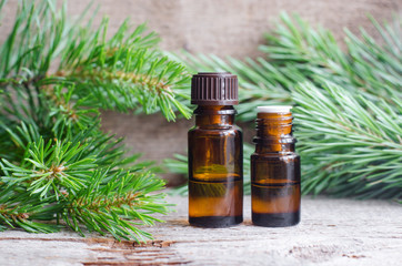 Two small bottles with essential pine oil (extract, tincture, infusion). Old wooden background. Aromatherapy, spa and herbal medicine concept. Copy space.